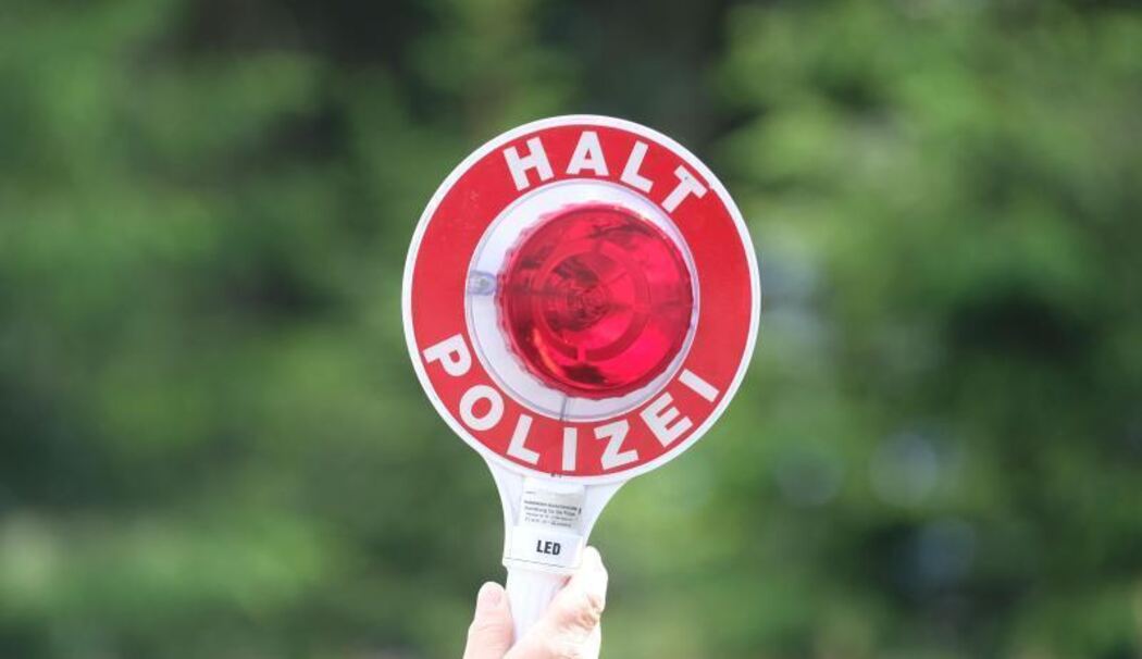 Eine Polizistin hält eine rote Winkerkelle in die Höhe