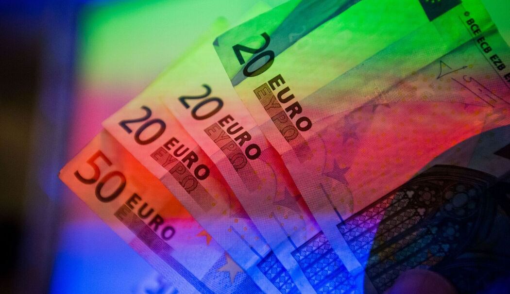 Geldscheine werden von einem Beamer farbig beleuchtet