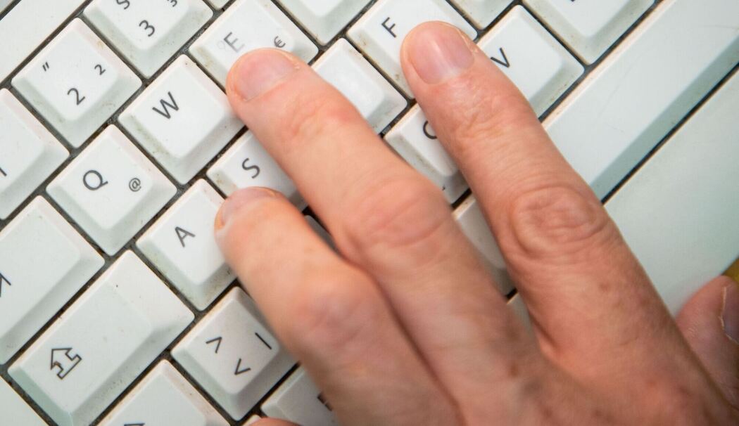 Mann tippt auf einer Tastatur
