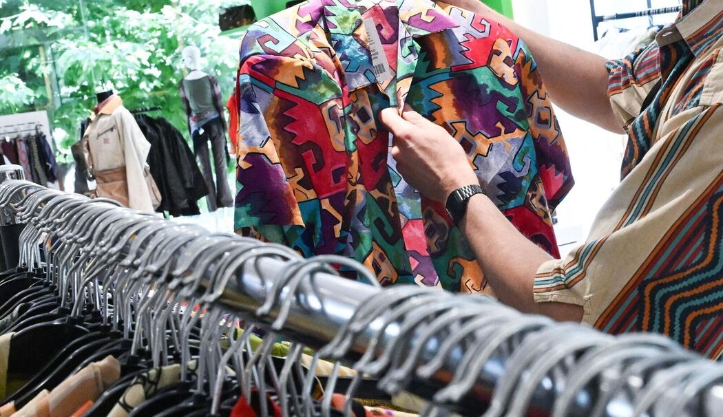 Ein Mitarbeiter sortiert Second Hand Bekleidung