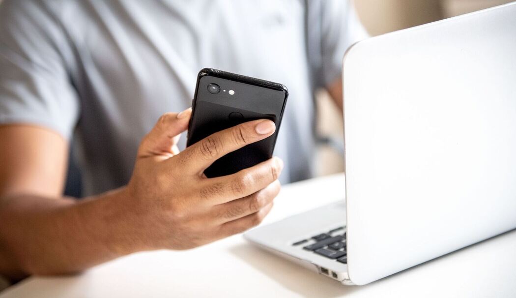 Mann mit Smartphone und Laptop