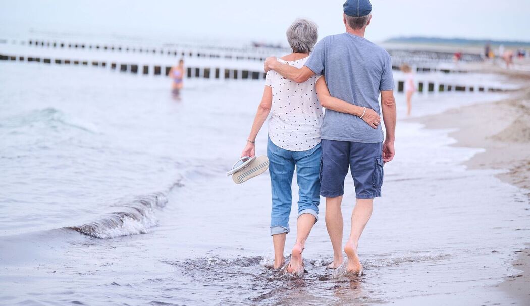 Ein Rentner-Paar spaziert am Strand entlang