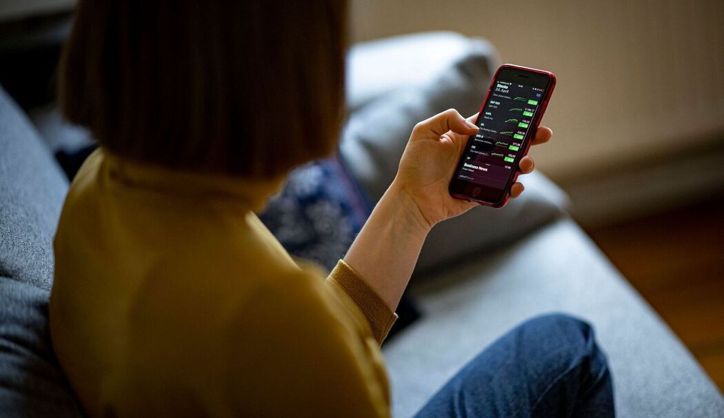 Eine Frau ruft Aktienkurse auf einem Smartphone auf