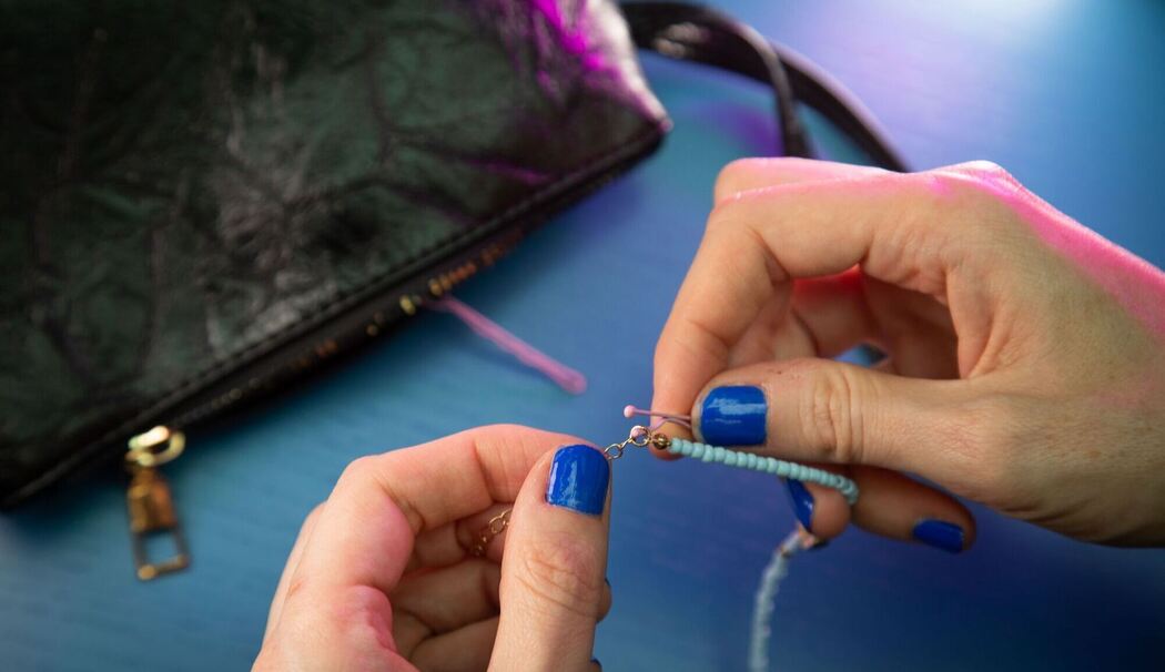 Frau fädelt eine Haarnadel durch das Kettenglied eines Armbands