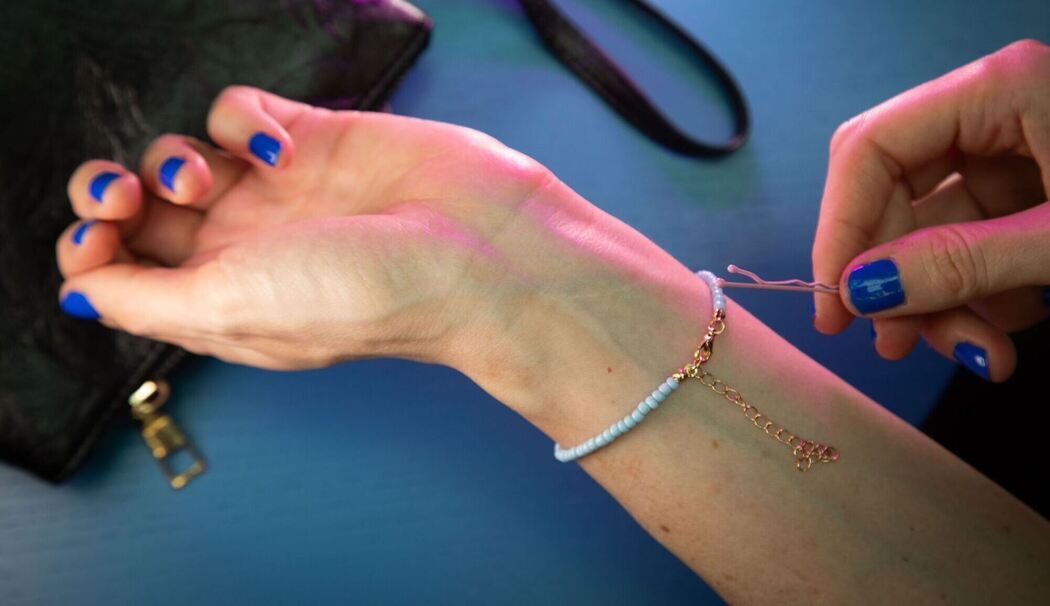 Frau legt Armband mit Hilfe einer Haarnadel an