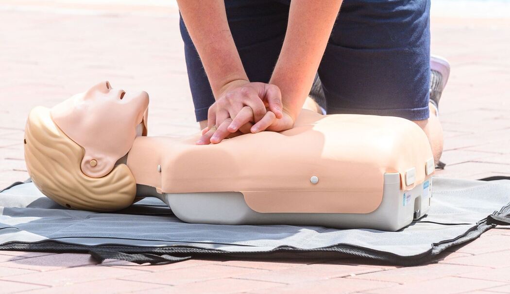 Eine Person übt eine Herzdruckmassage an einer Erste-Hilfe-Puppe