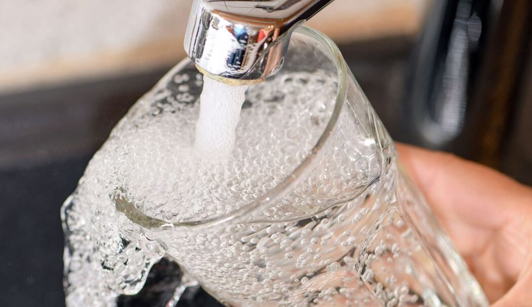 Eine Frau füllt ein Glas mit Trinkwasser aus dem Hahn