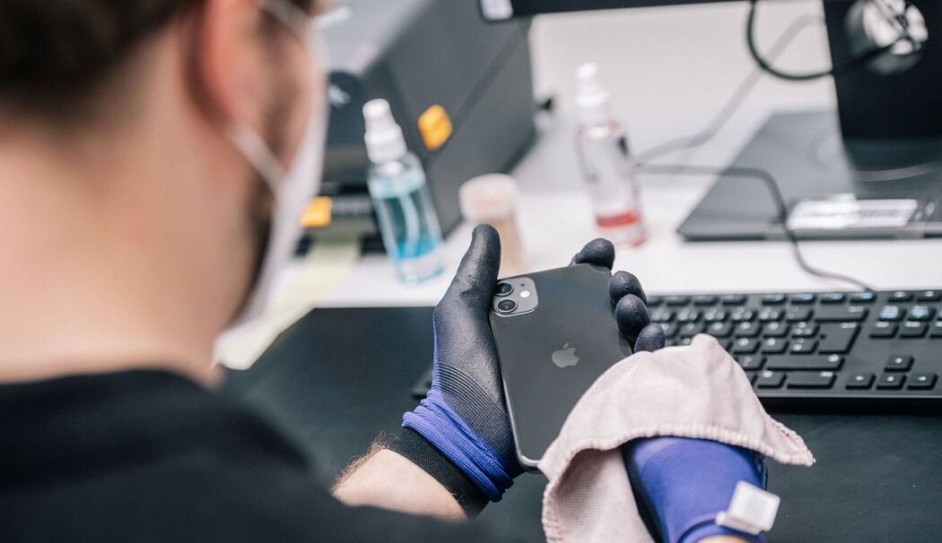 Ein Mitarbeiter überprüft ein refurbished Iphone