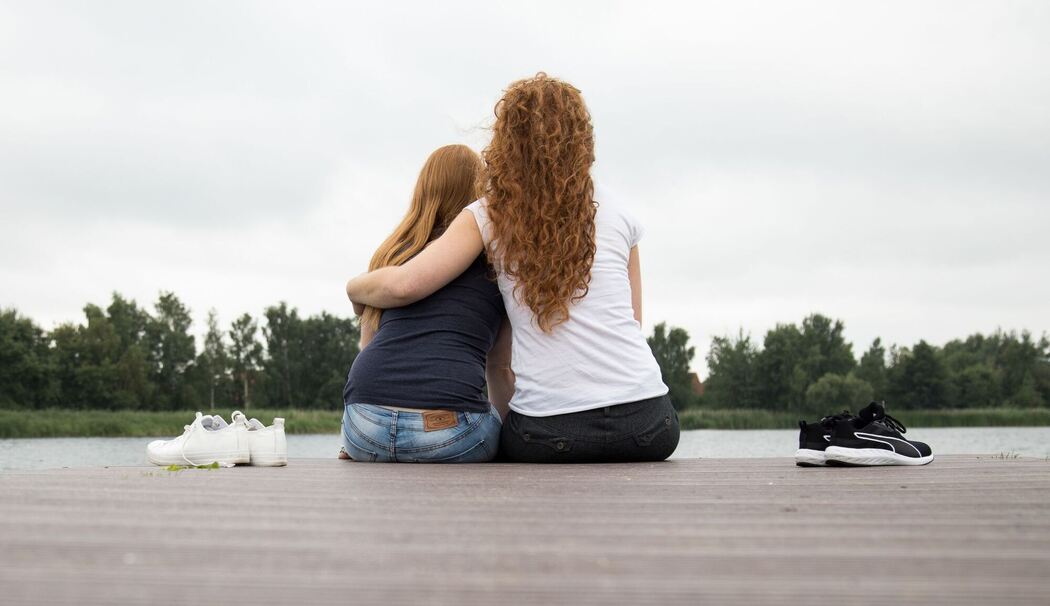 Zwei Frauen sitzen auf einem Steg am See