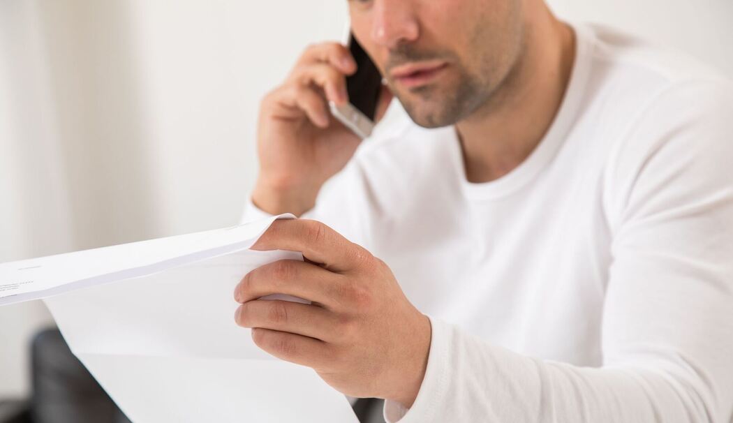 Ein Mann telefoniert und hält einen Brief in der Hand