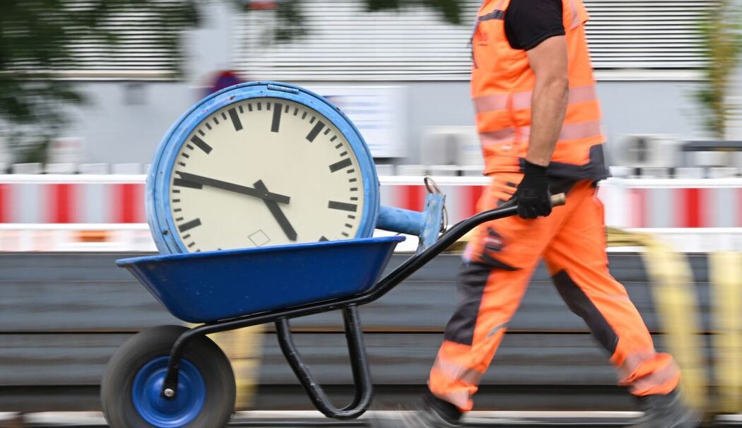 Ein Arbeiter transportiert eine Bahnhofsuhr auf einer Schubkarre