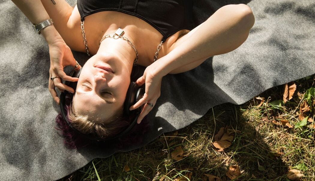 Eine diverse Person mit Kopfhörern im Park