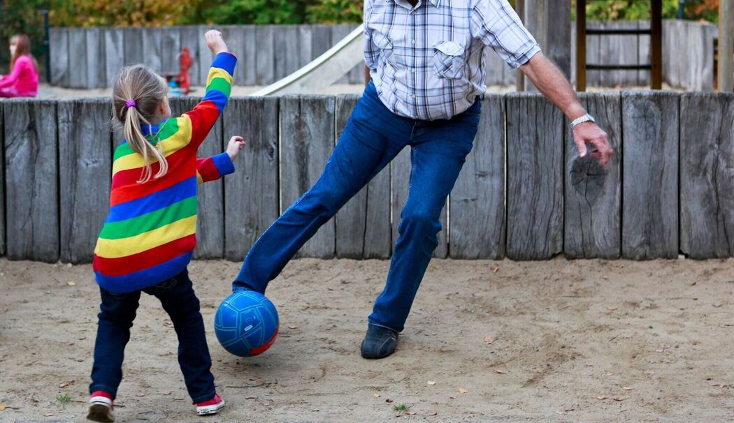 Ein Großvater spielt mit seinem Enkelkind Ball
