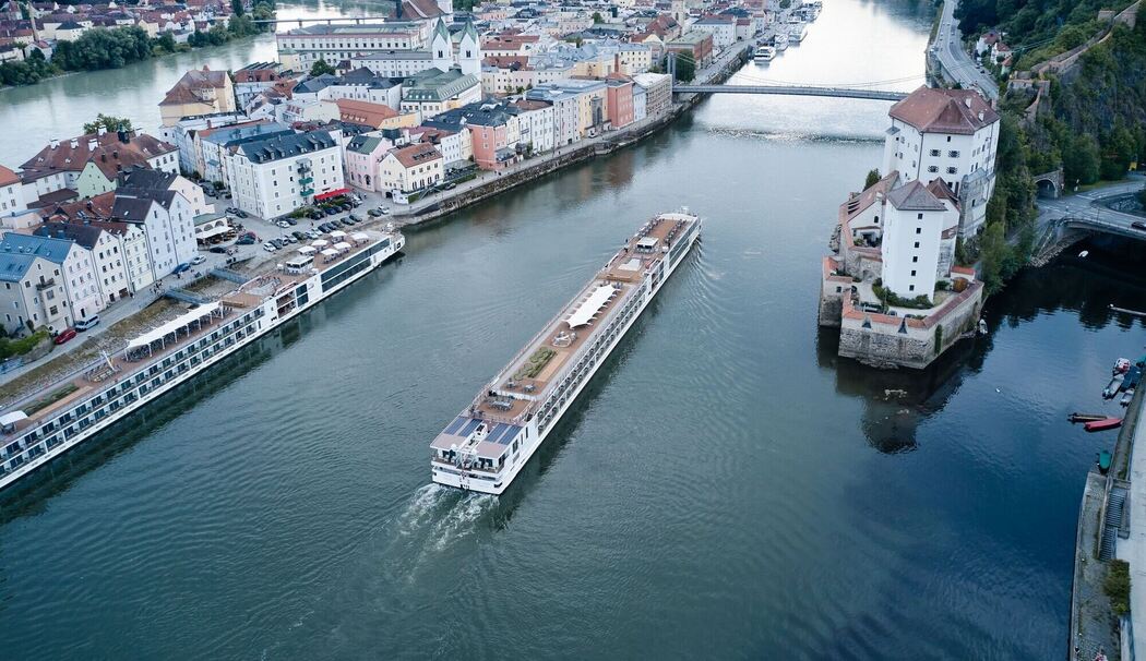 Ein Flusskreuzfahrtschiff fährt stromaufwärts an Passau vorbei