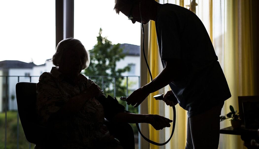 Eine Pflegekraft kontrolliert den Blutdruck einer älteren Dame