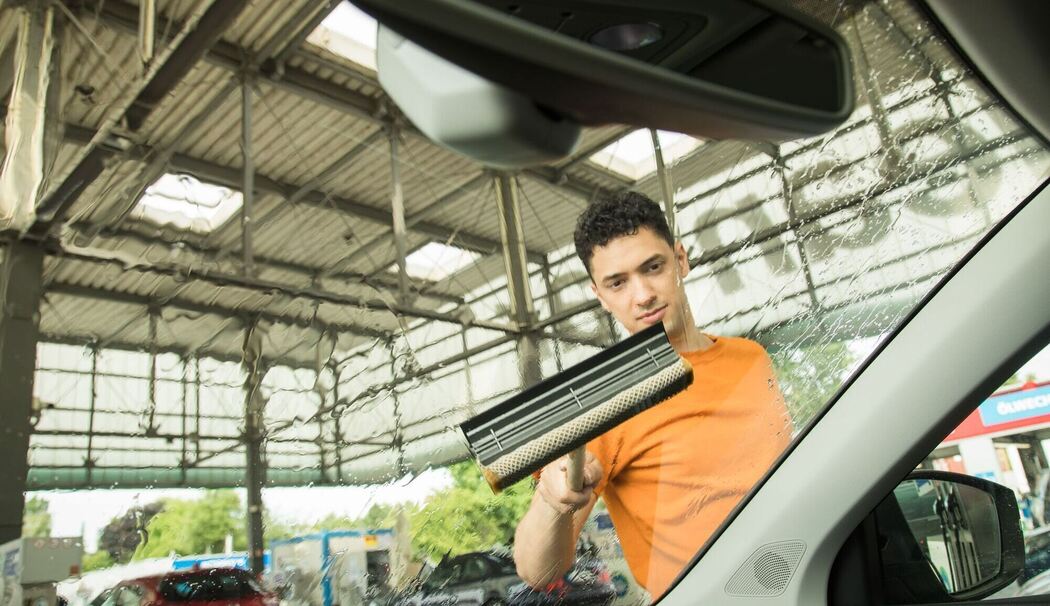 Ein Mann reinigt die Windschutzscheibe seines Autos