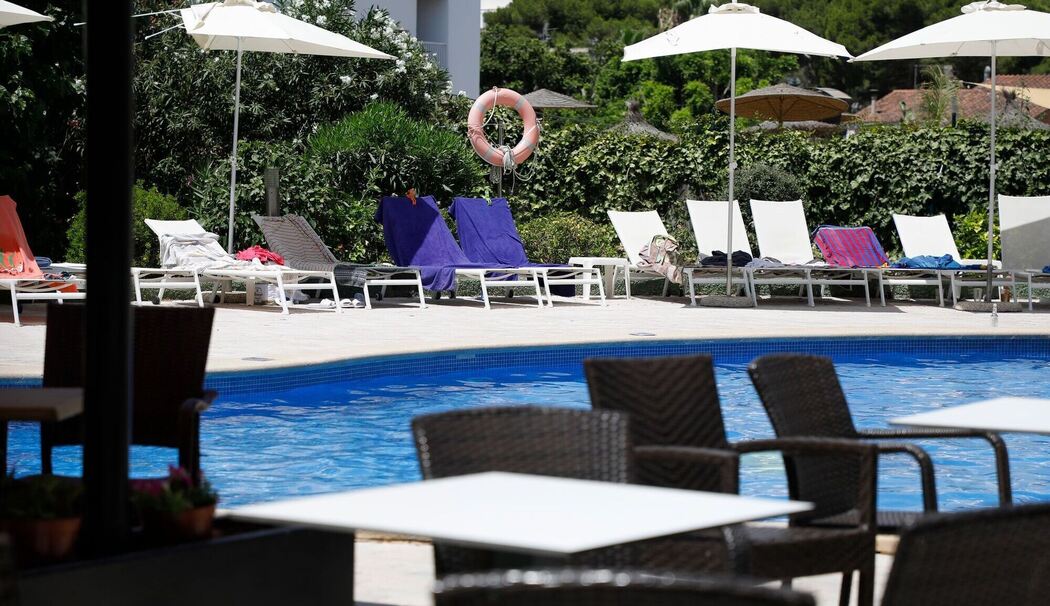 Handtücher liegen auf Sonnenliegen an einem Pool