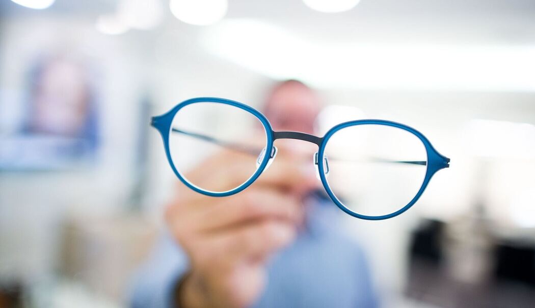 Optiker hält eine Brille in der Hand