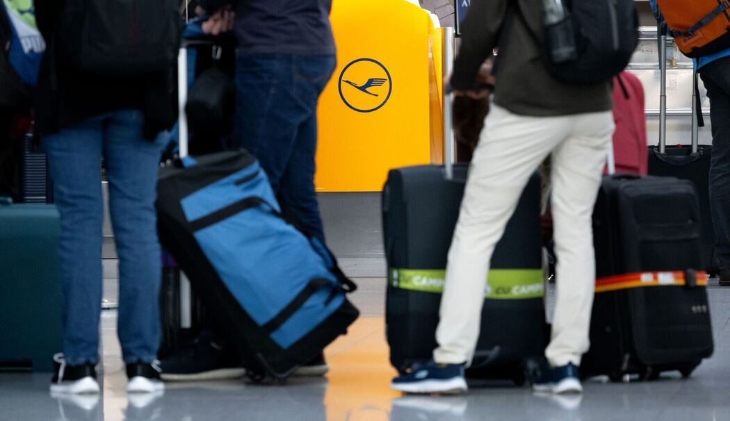 Passagiere warten an einem Check-In-Schalter der Lufthansa