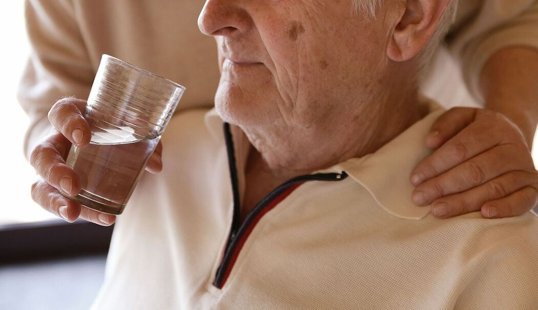 Eine Frau hilft einem Mann beim Trinken