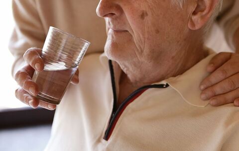Eine Frau hilft einem Mann beim Trinken