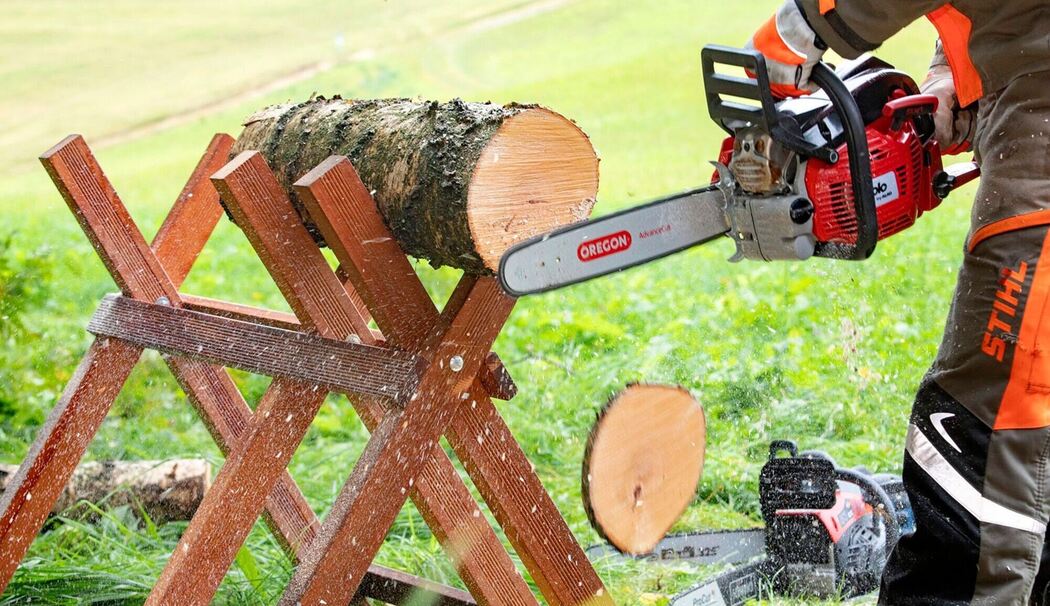 Ein Mann sägt einen 20-cm-Baumstamm mit einer Benzin-Motorsäge