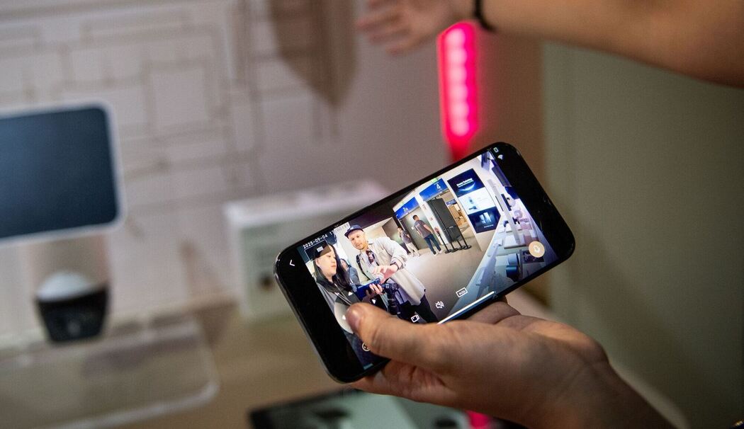 Eine Frau steuert mit einem Smartphone eine Ueberwachungskamera