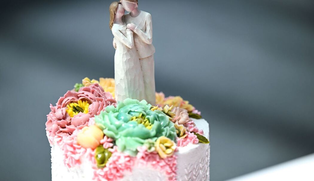 Die Figur eines Brautpaares steht auf einer Hochzeitstorte