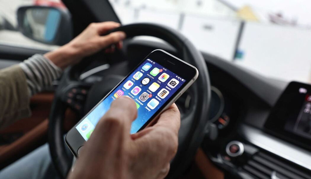 Eine Frau mit Handy am Steuer