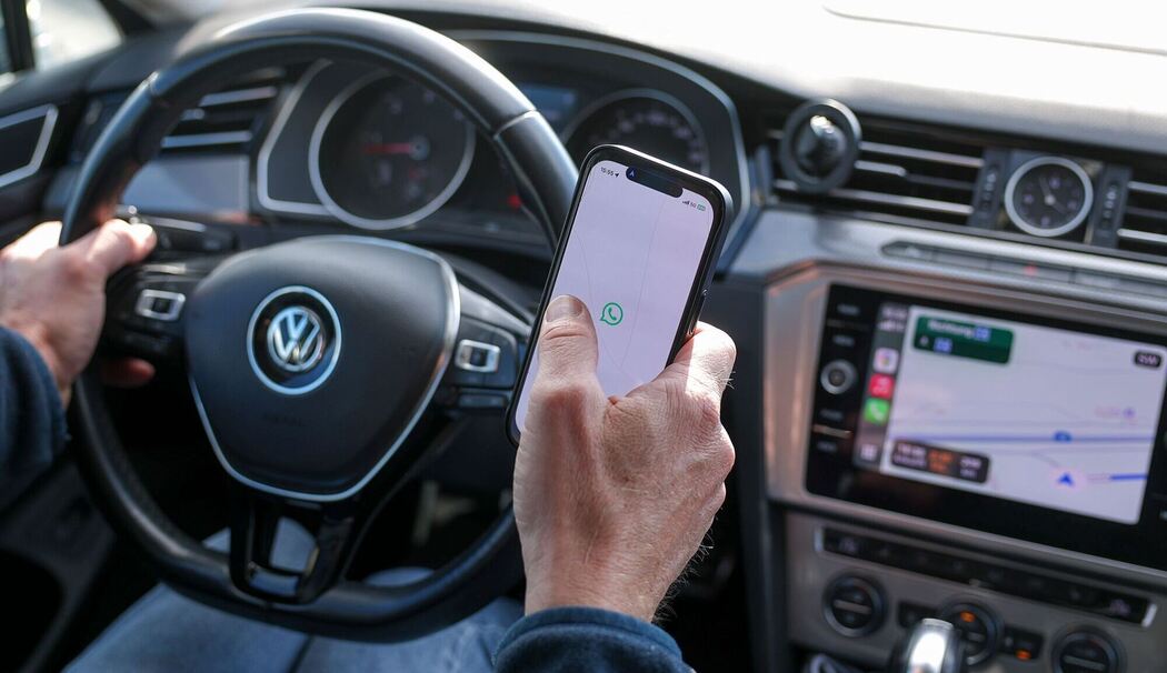 Ein Mann nutzt ein Smartphone am Steuer