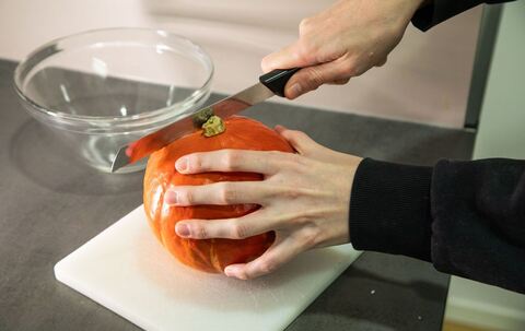 Frau schneidet einen Kürbis