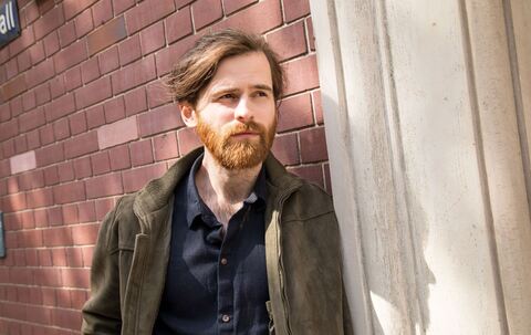 Ein Mann lehnt nachdenklich an einer Hauswand