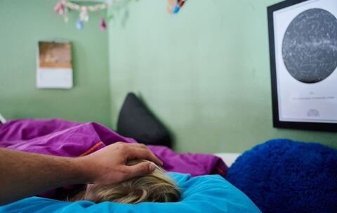 Ein Vater legt seine Hand auf den Kopf eines kranken Kindes