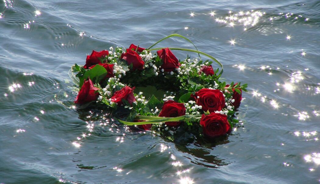 Blumen schwimmen bei einer Seebestattung auf dem Wasser