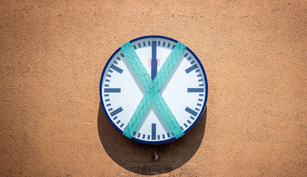 Eine abgeklebte Bahnhofsuhr hängt an einer Wand