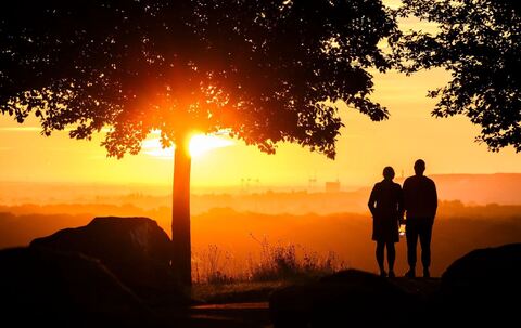 Ein Paar steht bei Sonnenaufgang auf einem Berg