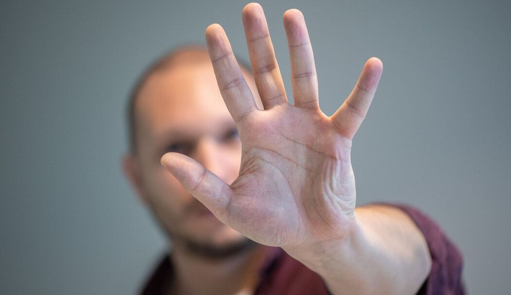Ein Mann hebt schützend die Hand vor sein Gesicht