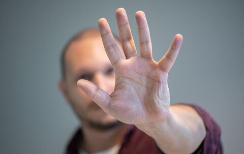Ein Mann hebt schützend die Hand vor sein Gesicht