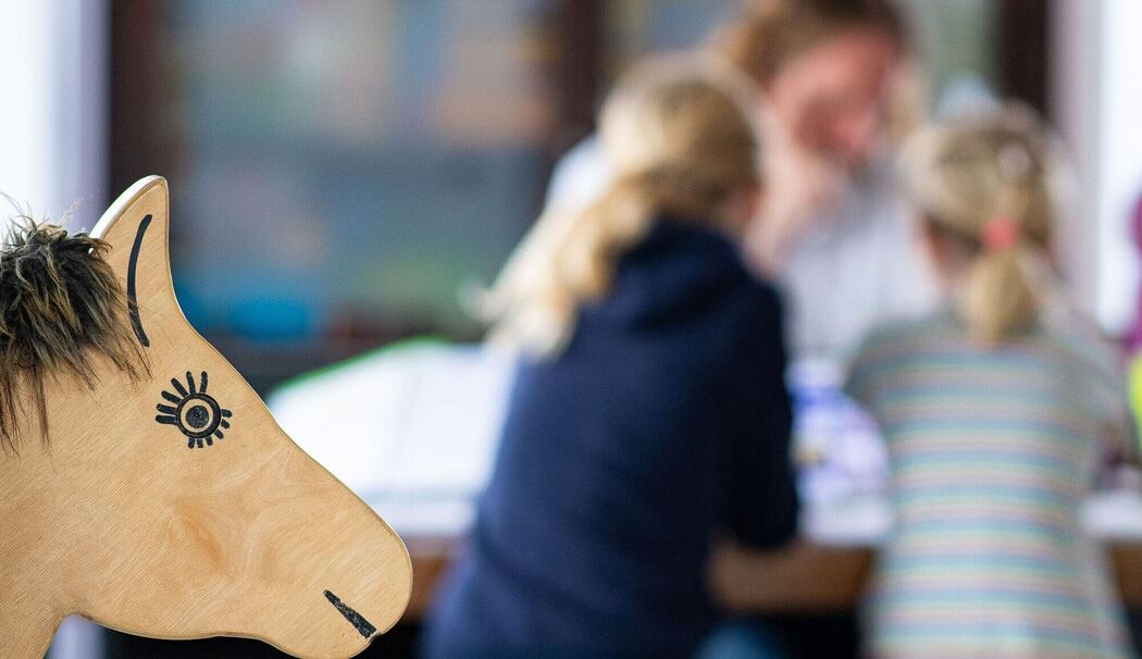 Ein Elternteil sitzt mit seinen Kindern an einem Tisch