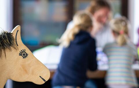 Ein Elternteil sitzt mit seinen Kindern an einem Tisch