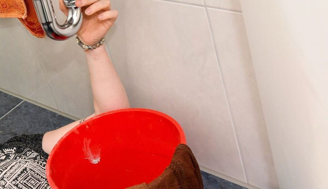 Mann repariert einen Siphon am Waschbecken