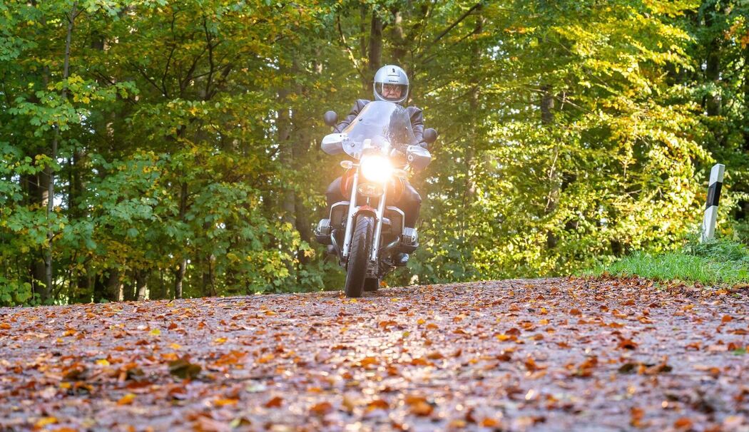 Motorradfahrer fährt über eine herbstliche Landstraße