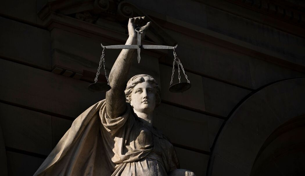 Vor einem Justizgebäude steht die Statue der Justitia