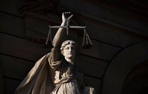 Vor einem Justizgebäude steht die Statue der Justitia