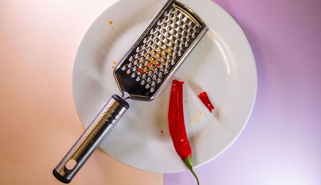 Gebrochene Chili liegt neben einer Küchenreibe