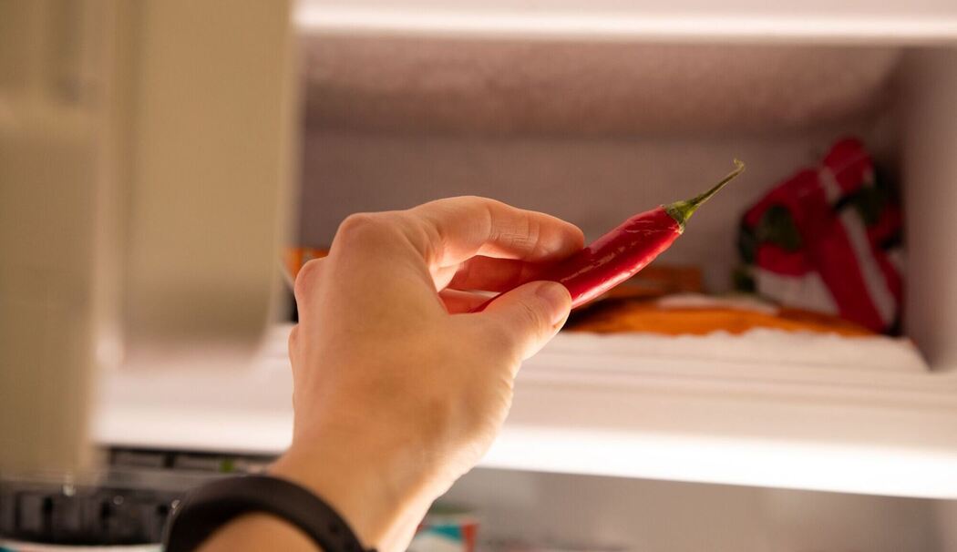 Eine Frau legt eine Chili in ein Eisfach