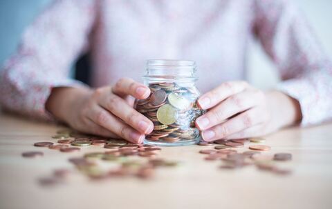 Eine Frau hält ein mit Münzen gefülltes Glas