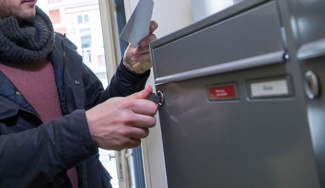 Ein Mann holt einen Brief aus dem Briefkasten Ein Mann holt einen Brief aus dem Briefkasten