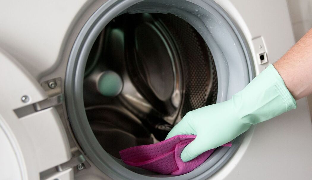 Eine Person reinigt die Gummidichtung einer Waschmaschine Eine Person reinigt die Gummidichtung einer Waschmaschine
