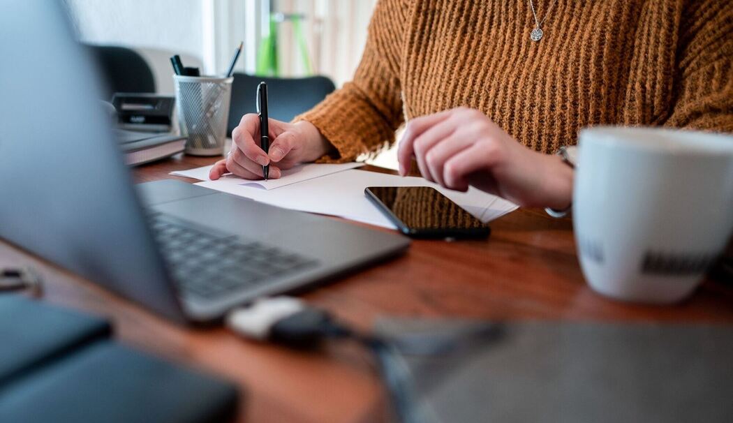 Frau sitzt mit einem Laptop am Tisch
